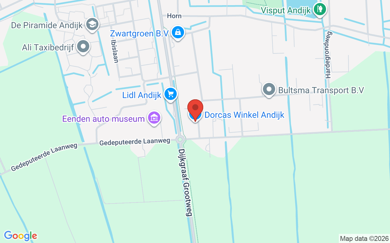 Gezicht op de Dorcas Winkel in Andijk, gelegen aan de Gedeputeerde Laanweg, met nabijgelegen winkels en transportmogelijkheden.