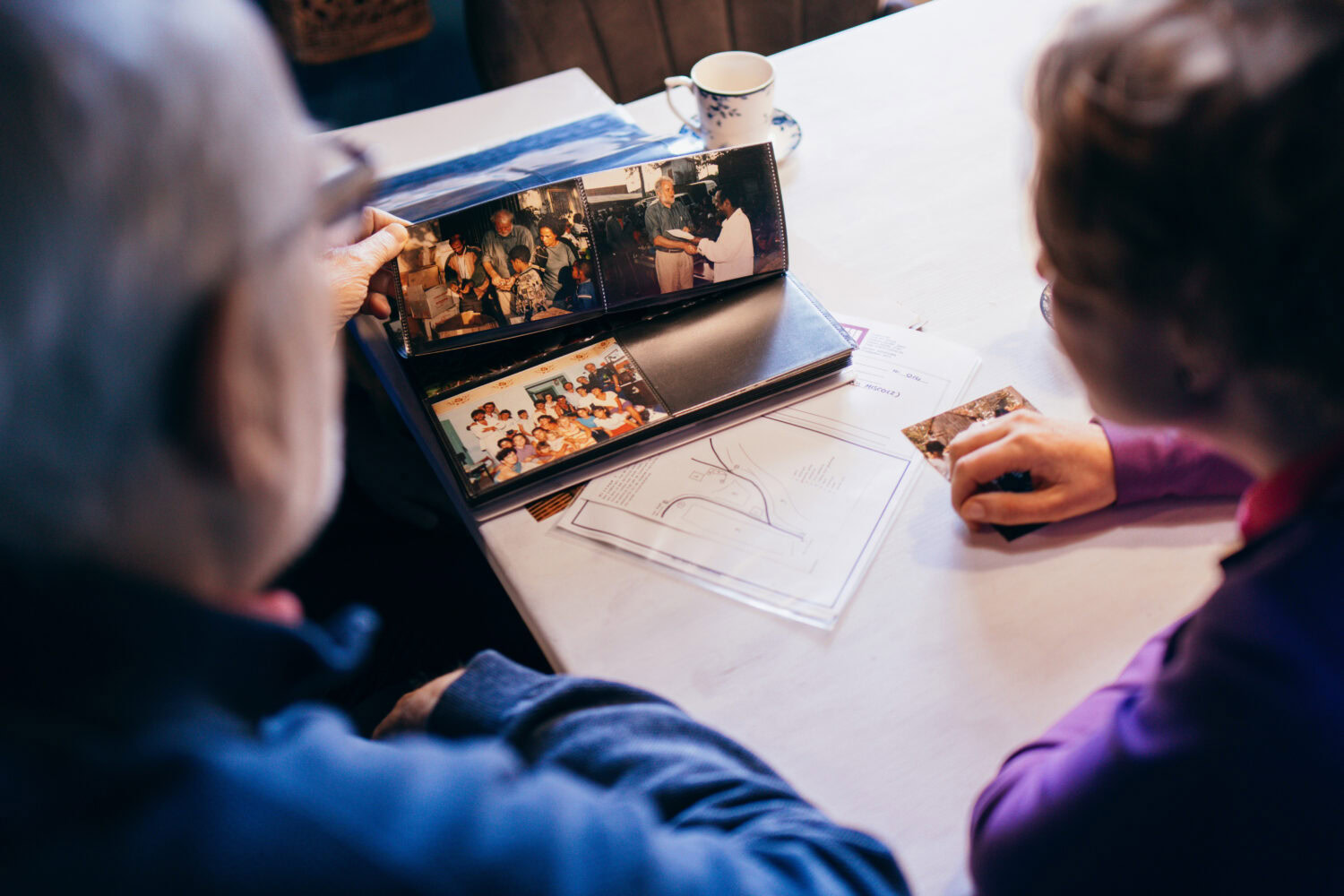 Dirk Jan Groot en Janneke bekijken een fotoboek op aan de tafel.