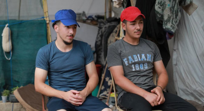 Twee jonge mannen zitten samen in een tent,