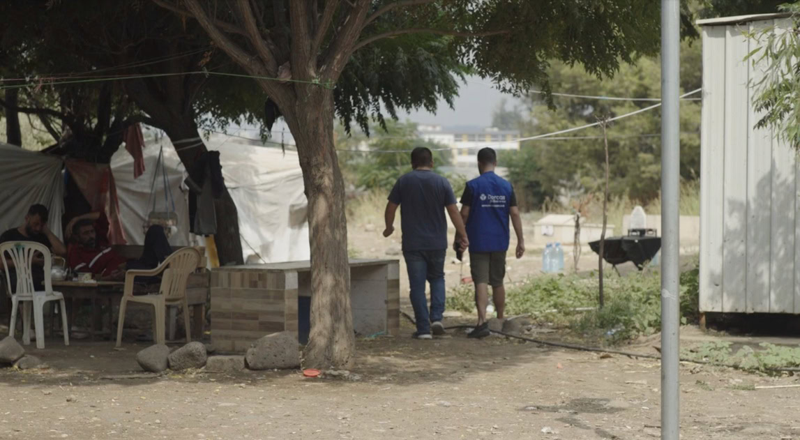 Mensen wandelen door een tentenkamp waar voedselpakketten worden uitgedeeld