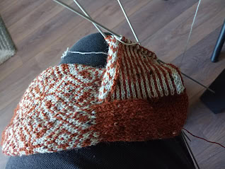 Veelzijdige breiwerk op naald, klaar voor verdere afwerking, met verschillende texturen en kleuren voor een uniek handgemaakt project.