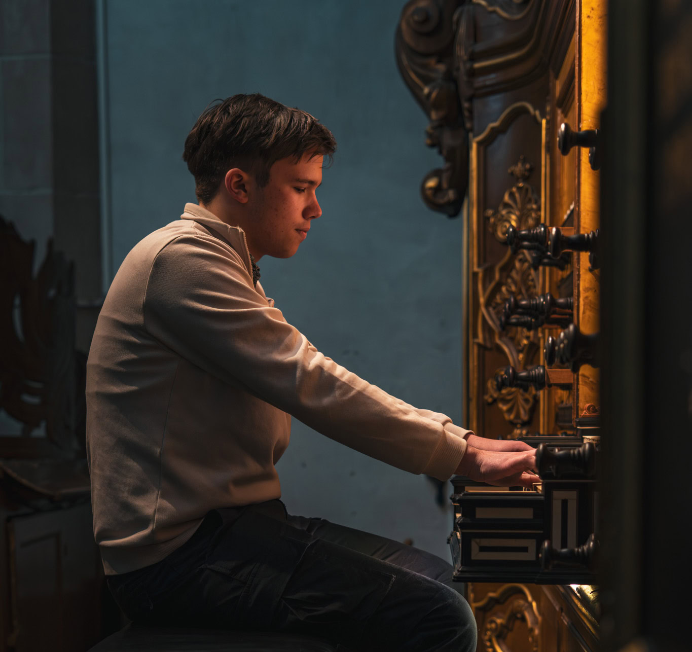 Jongeman speelt orgel in de Bovenkerk in Kampen tijdens een benefietactie voor Dorcas, met focus op zijn concentratie en de historische orgel.