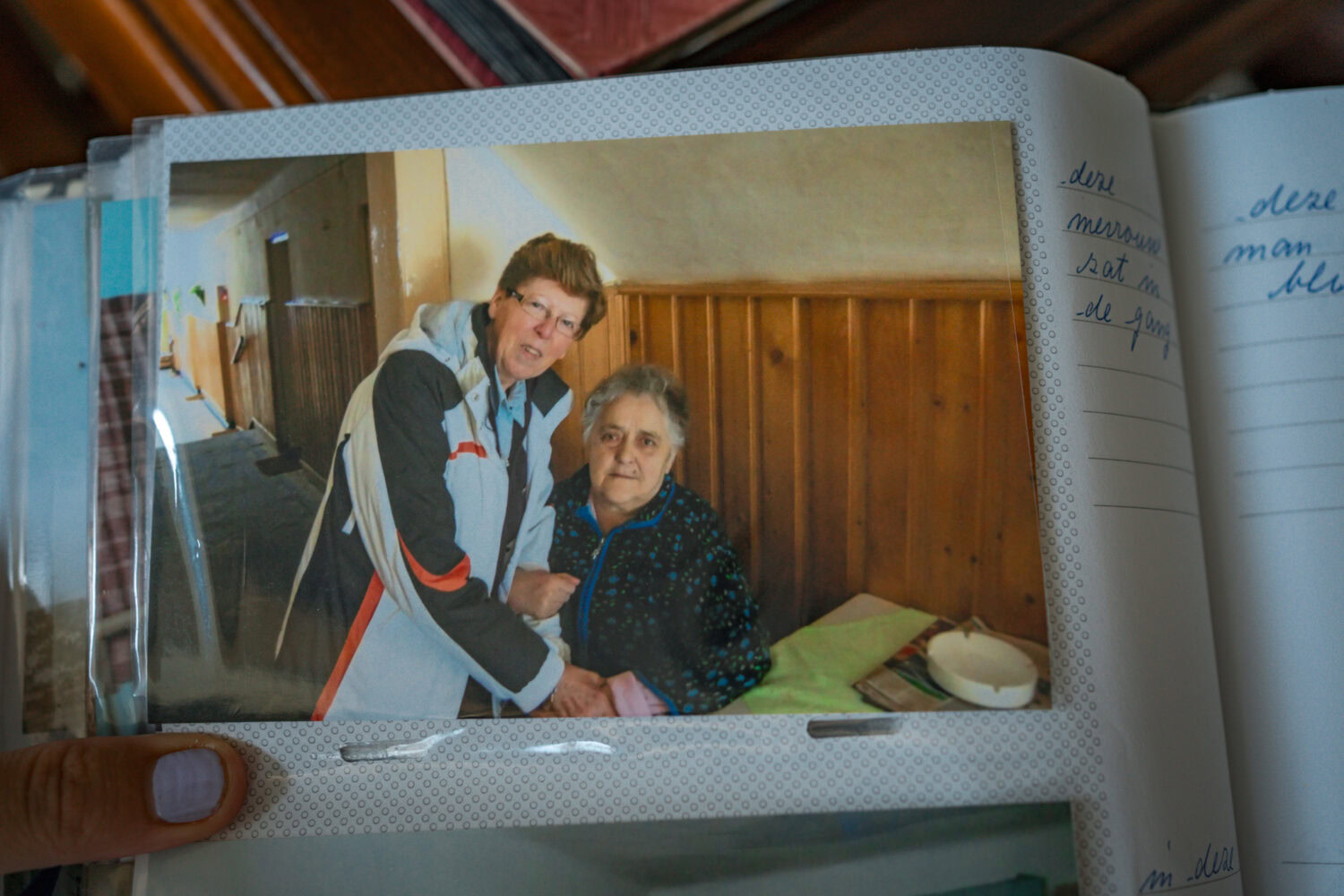 Hulpverlener bij zorgbezoek aan oudere vrouw in huis met houten wandbekleding.