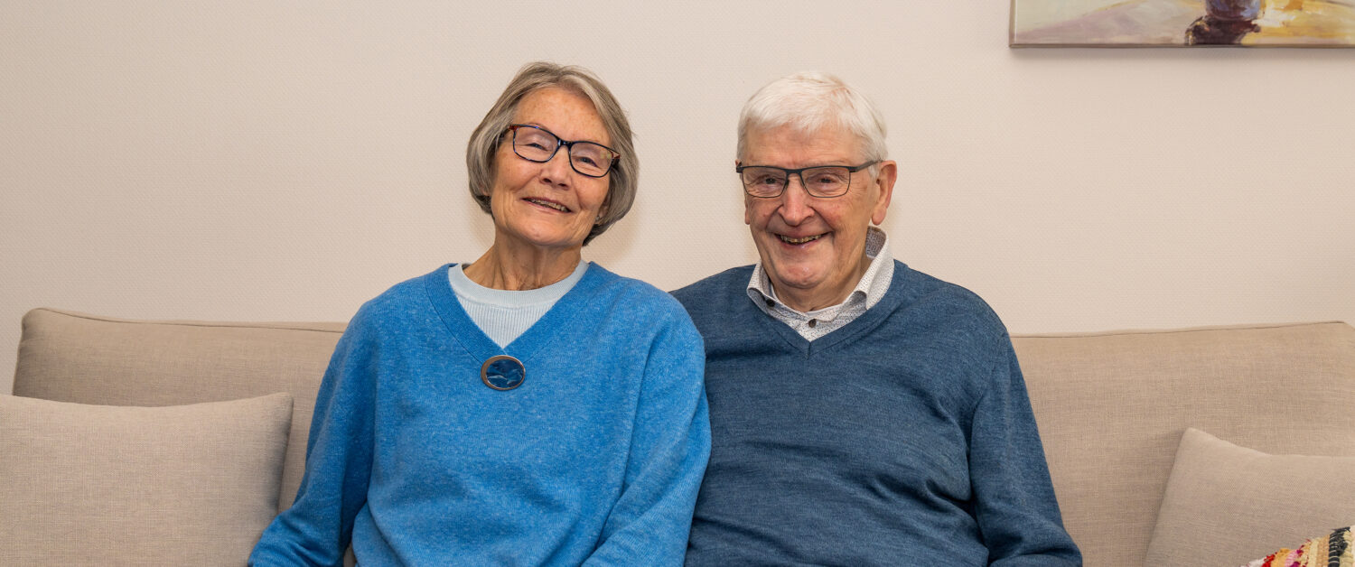 Een gelukkige oudere koppel zit samen op een bank, lachend en genietend van elkaars gezelschap, symboliseert verbondenheid en geluk in de latere jaren.
